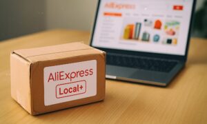 Paket s oznakom AliExpress Local+ na stolu ispred otvorenog laptopa s prikazom internetske trgovine AliExpress, simbolizira novu lokalnu logističku uslugu za bržu dostavu u Europi.
