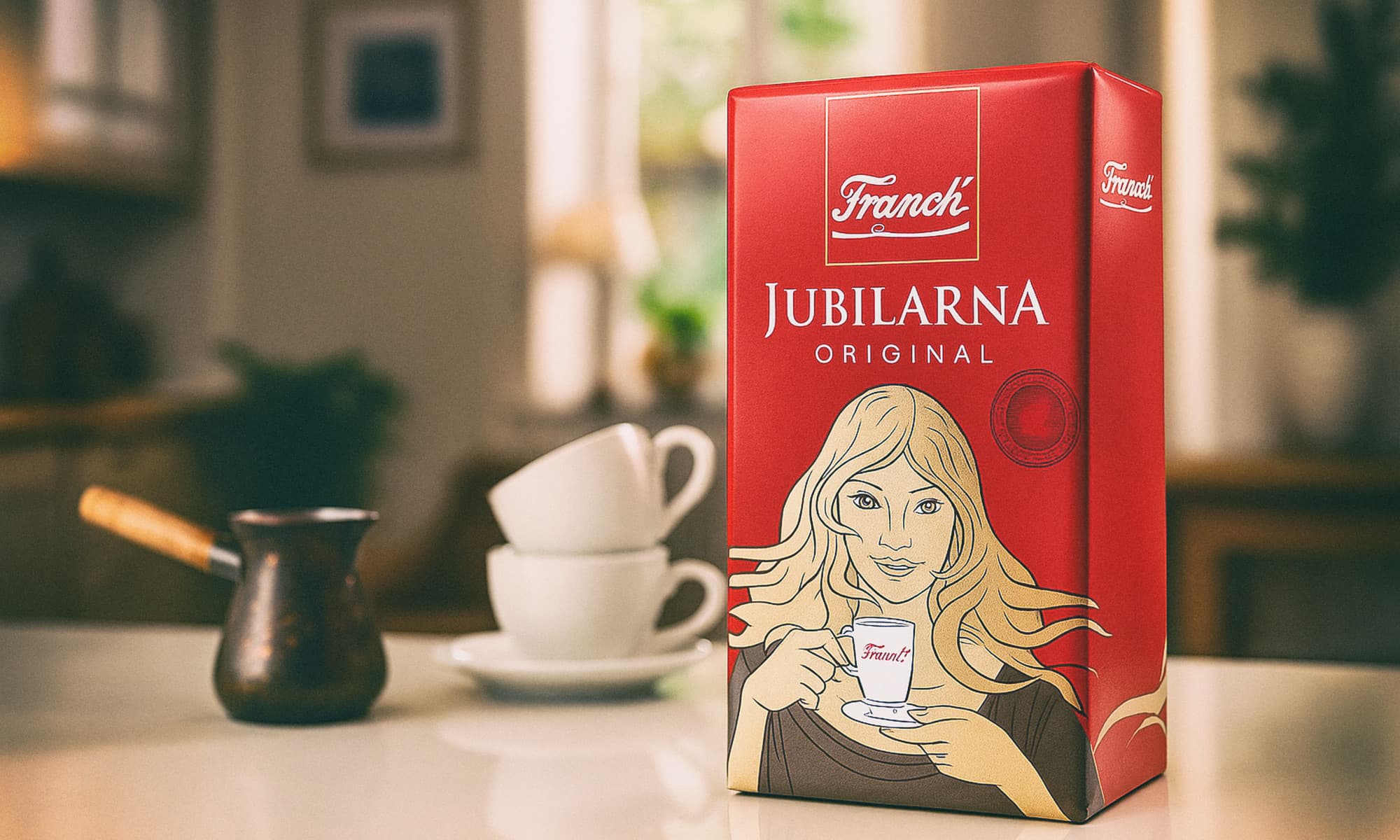 Pakiranje Franck Jubilarne mljevene kave na stolu, uz džezvu i dvije šalice u pozadini.