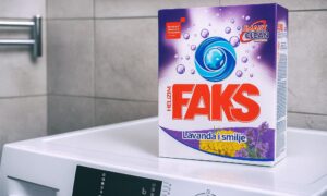 Kutija deterdženta za pranje rublja Faks Helizim s mirisom lavande i smilja, postavljena na perilicu rublja u kupaonici.