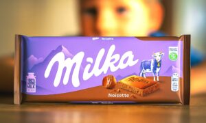 Milka Noisette čokolada na stolu, u pozadini zamućeno dječje lice.