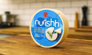Pakiranje veganske zamjene za sir Nurishh Coeur Fleuri na drvenoj radnoj površini u kuhinji.