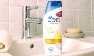 Bočica šampona Head & Shoulders Citrus Fresh na rubu umivaonika u modernoj kupaonici, s kromiranom slavinom i sapunom u pozadini.