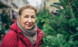 Žena kupuje božićnu jelku na tržnici.